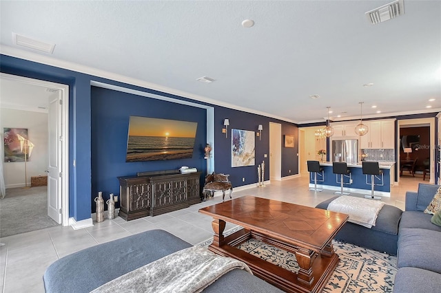 living room with visible vents, crown molding, baseboards, and light tile patterned floors