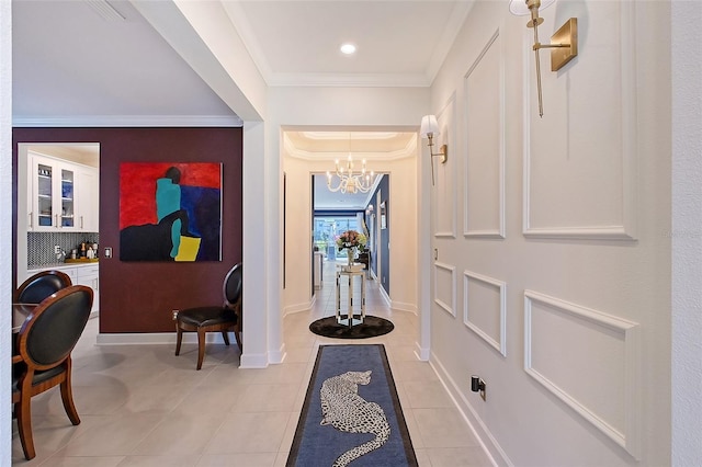 foyer entrance with light tile patterned floors, baseboards, ornamental molding, and a chandelier