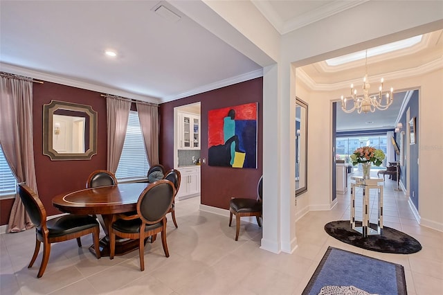 dining room featuring a tray ceiling, a notable chandelier, crown molding, visible vents, and baseboards