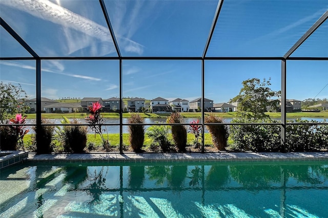 outdoor pool with glass enclosure, a water view, and a residential view