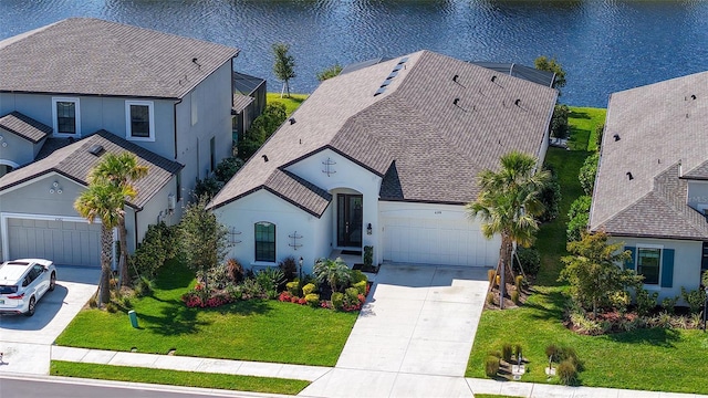 view of front of property featuring a front lawn, a water view, driveway, and an attached garage