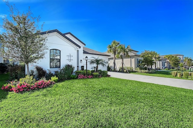 mediterranean / spanish home featuring stucco siding, concrete driveway, a front lawn, and a garage