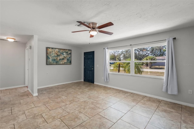 spare room with light tile patterned floors, ceiling fan, baseboards, and a textured ceiling