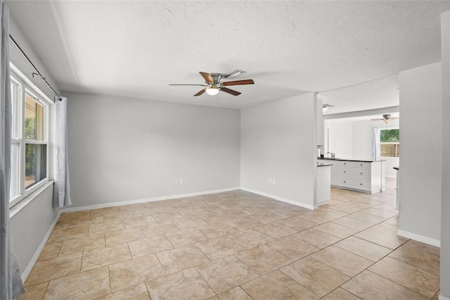 unfurnished room with a textured ceiling, plenty of natural light, and a ceiling fan