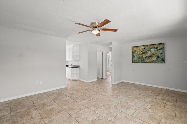 empty room featuring a ceiling fan, a textured ceiling, and baseboards