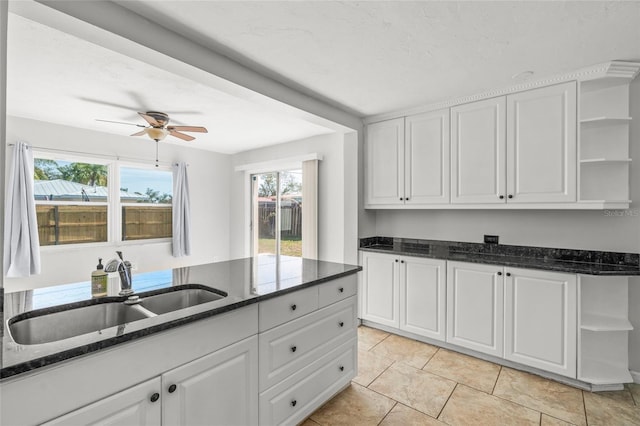 kitchen featuring white cabinetry, open shelves, a sink, and dark stone counters