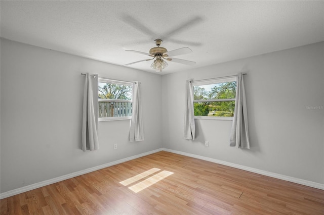 empty room featuring light wood-style floors, ceiling fan, baseboards, and a textured ceiling