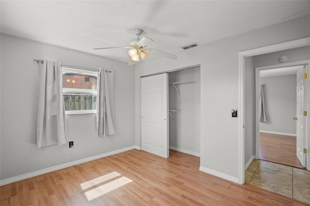 unfurnished bedroom with light wood finished floors, baseboards, visible vents, and a closet