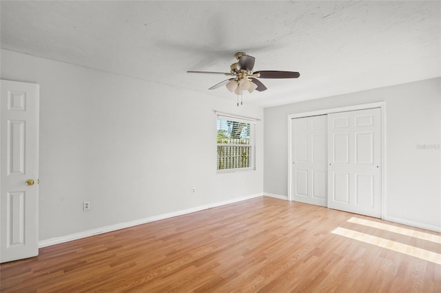 unfurnished bedroom featuring light wood-style floors, ceiling fan, baseboards, and a closet