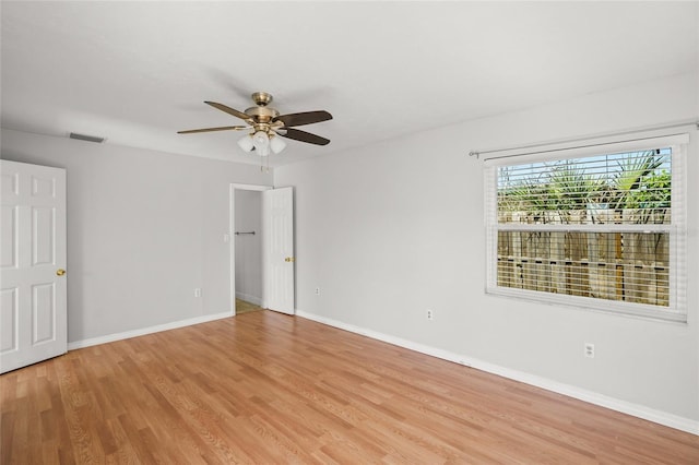 unfurnished room featuring light wood finished floors, a ceiling fan, visible vents, and baseboards