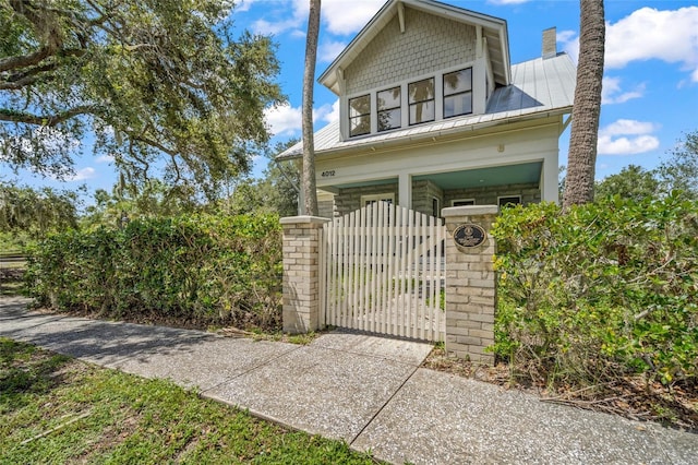 view of front of house with metal roof, a standing seam roof, a fenced front yard, and a gate