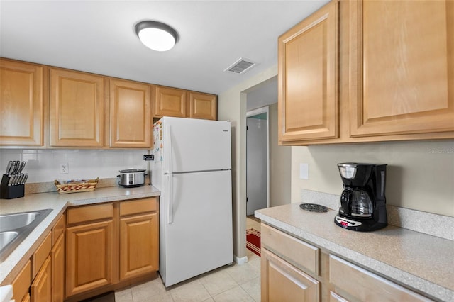 kitchen with light tile patterned flooring, a sink, visible vents, light countertops, and freestanding refrigerator