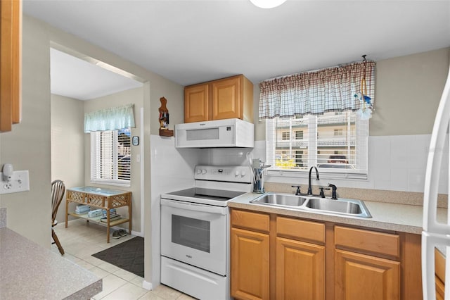 kitchen featuring a healthy amount of sunlight, white appliances, light countertops, and a sink