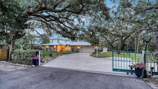 view of front of home featuring metal roof, concrete driveway, an attached garage, and fence