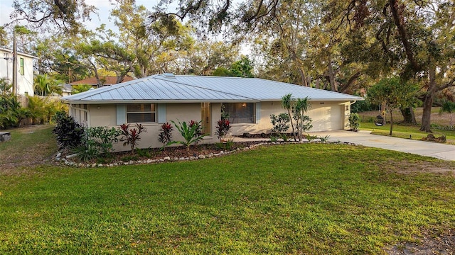 ranch-style home featuring metal roof, an attached garage, driveway, stucco siding, and a front yard