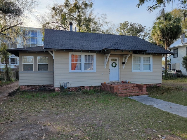 bungalow-style house with crawl space, a shingled roof, and a front yard