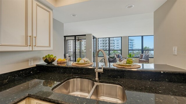 kitchen with open floor plan, dark stone countertops, a sink, and recessed lighting