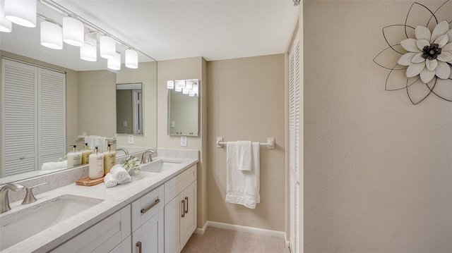 full bath with a closet, a sink, baseboards, and double vanity