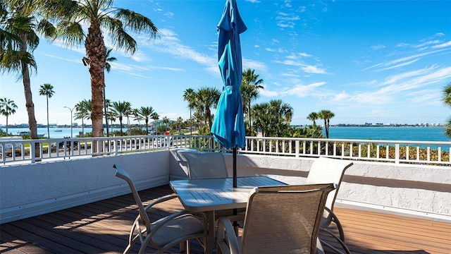 deck with a water view and outdoor dining area