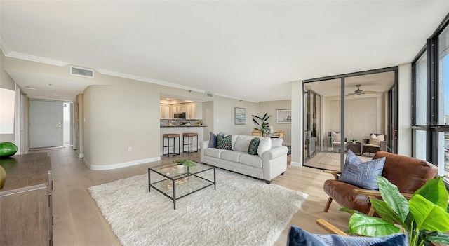 living area featuring floor to ceiling windows, crown molding, visible vents, light wood-style floors, and baseboards