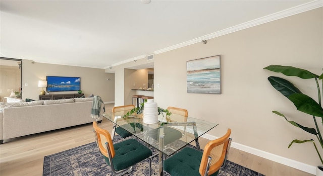 dining space with ornamental molding, visible vents, baseboards, and wood finished floors