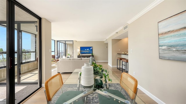 dining room with light wood-type flooring, baseboards, floor to ceiling windows, and crown molding