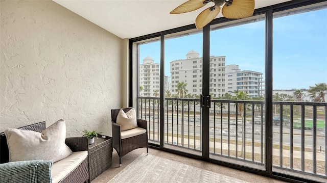 sunroom / solarium featuring a healthy amount of sunlight, a ceiling fan, and a city view