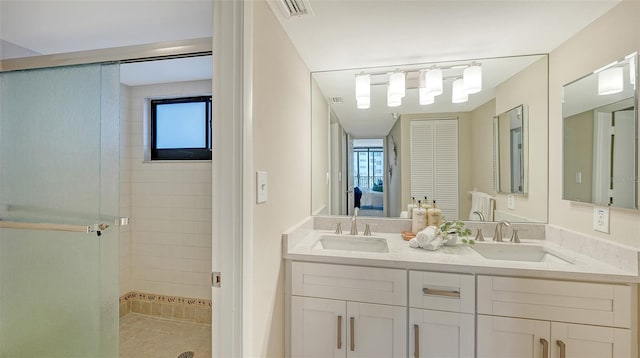 full bath with double vanity, a sink, visible vents, and a shower stall