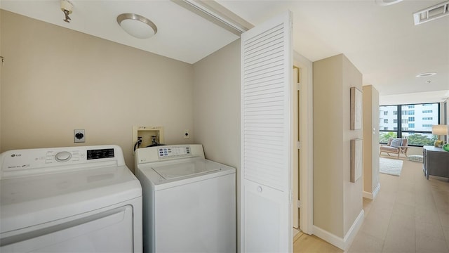 washroom featuring light wood-style flooring, laundry area, visible vents, baseboards, and washer and dryer