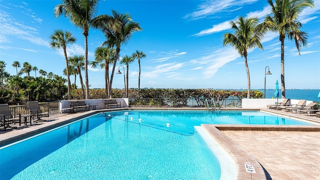 community pool with a patio area and fence