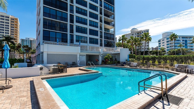 community pool with fence, a city view, and a patio