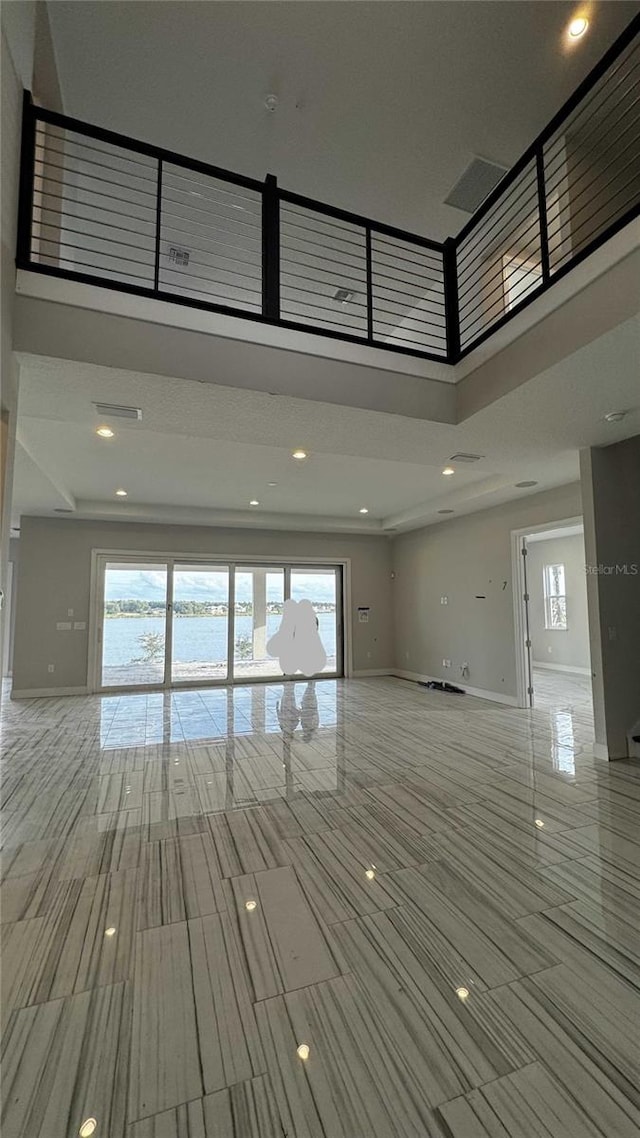 unfurnished living room with baseboards, plenty of natural light, and a high ceiling