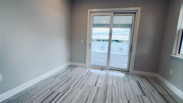 spare room featuring wood finish floors and baseboards