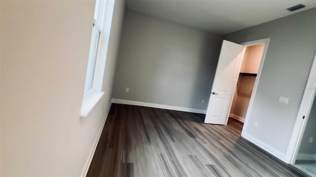 unfurnished bedroom with baseboards, visible vents, and wood finished floors