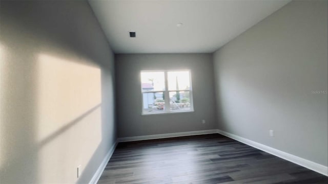 spare room with dark wood-style flooring and baseboards