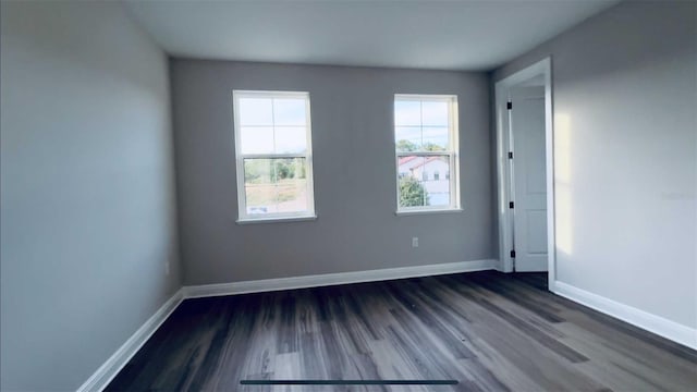 empty room featuring baseboards and dark wood finished floors