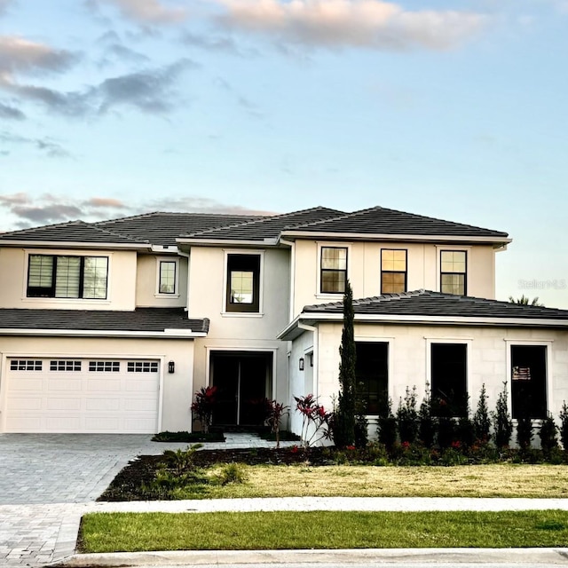 16832 Bolsena Dr, Bella Collina, FL 34756 - view of front facade featuring a garage, decorative driveway, a front lawn, and stucco siding