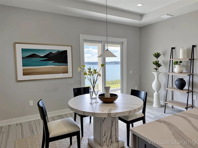16832 Bolsena Dr, Bella Collina, FL 34756 - dining space featuring light wood-type flooring, baseboards, recessed lighting, a water view, and a tray ceiling