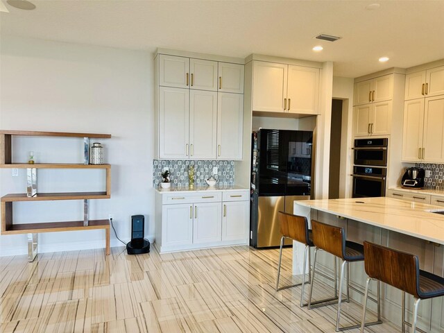 16832 Bolsena Dr, Bella Collina, FL 34756 - kitchen with freestanding refrigerator, multiple ovens, decorative backsplash, a breakfast bar, and recessed lighting
