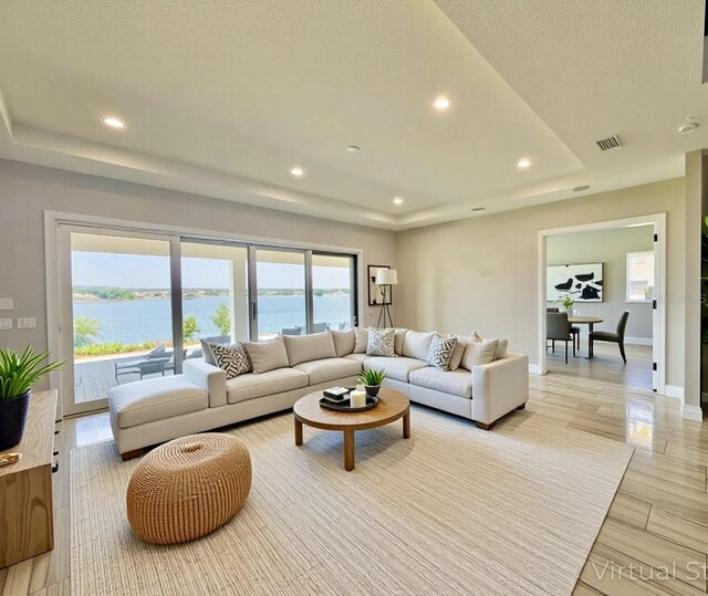 16832 Bolsena Dr, Bella Collina, FL 34756 - living area with a raised ceiling, recessed lighting, a water view, and baseboards
