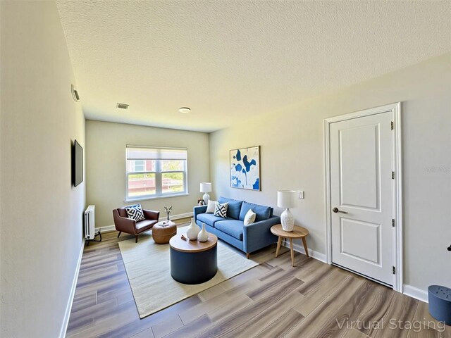 16832 Bolsena Dr, Bella Collina, FL 34756 - living room with wood finished floors, radiator heating unit, a textured ceiling, and baseboards