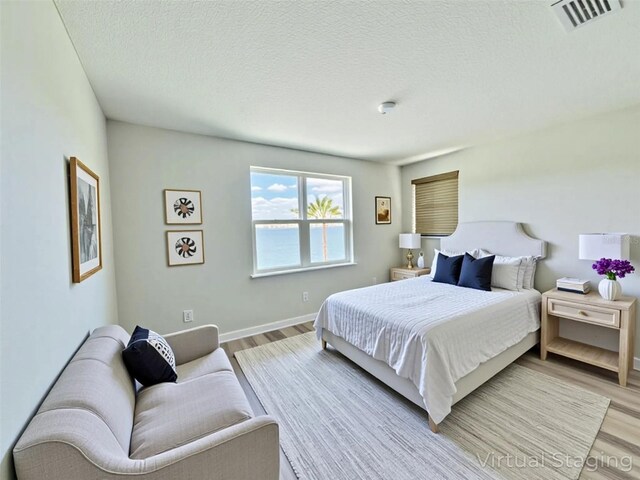16832 Bolsena Dr, Bella Collina, FL 34756 - bedroom with light wood-style flooring, a textured ceiling, and baseboards