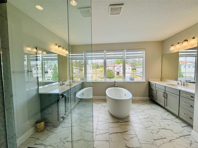 16832 Bolsena Dr, Bella Collina, FL 34756 - full bath with baseboards, marble look tile flooring, vanity, a freestanding tub, and a textured ceiling