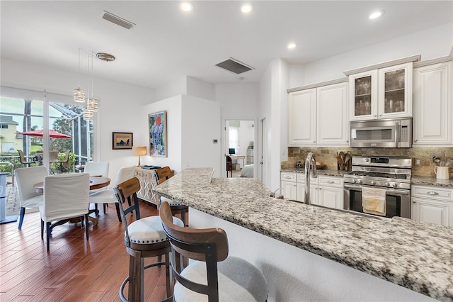 kitchen with tasteful backsplash, visible vents, appliances with stainless steel finishes, and a breakfast bar