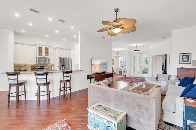 living room with recessed lighting, visible vents, wood finished floors, and ceiling fan with notable chandelier