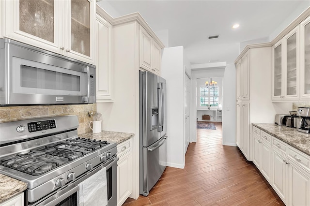 kitchen featuring light stone countertops, visible vents, an inviting chandelier, appliances with stainless steel finishes, and light wood-type flooring