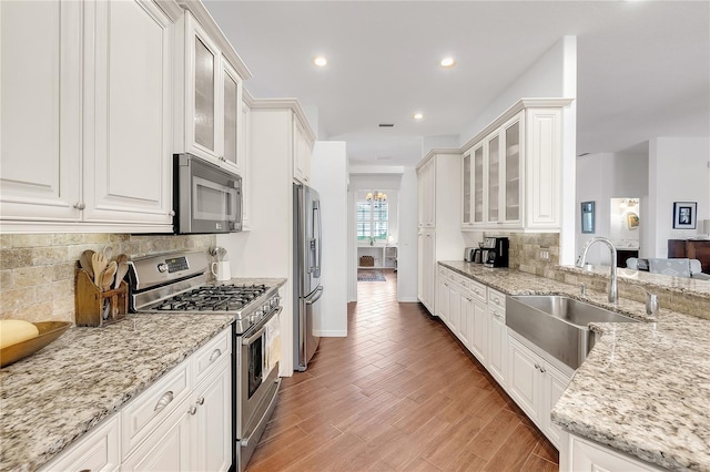 kitchen with white cabinetry, stainless steel appliances, light wood-type flooring, and a sink