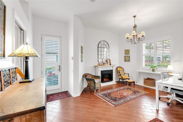 office space featuring a lit fireplace, baseboards, an inviting chandelier, and wood finished floors