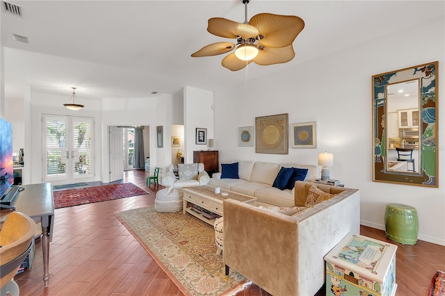 living area with wood finished floors, baseboards, visible vents, ceiling fan, and french doors