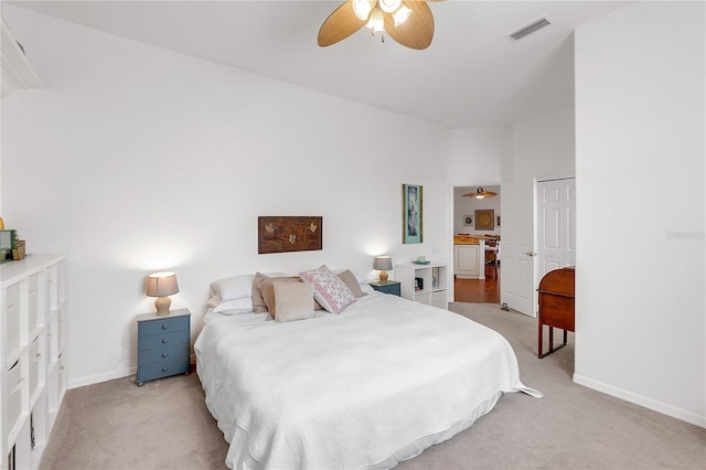 bedroom featuring a ceiling fan, visible vents, baseboards, light colored carpet, and connected bathroom